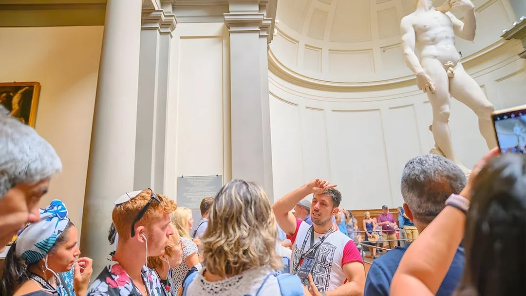 Tour group with guide at Accademia Gallery, Florence, viewing Michelangelo's David statue.