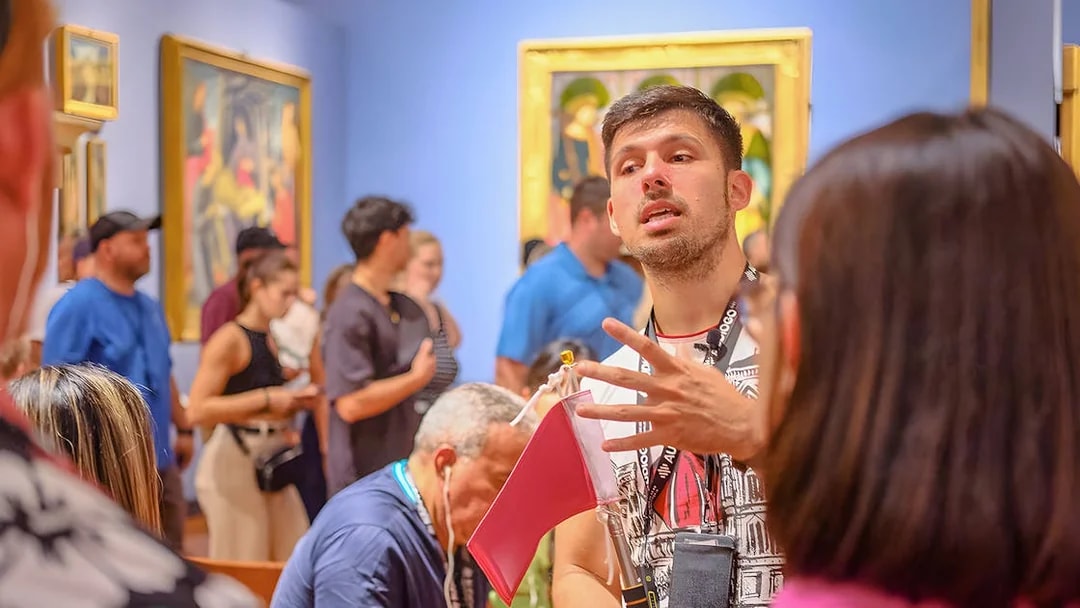 Guide explaining artwork to tourists at Accademia Gallery, Florence.