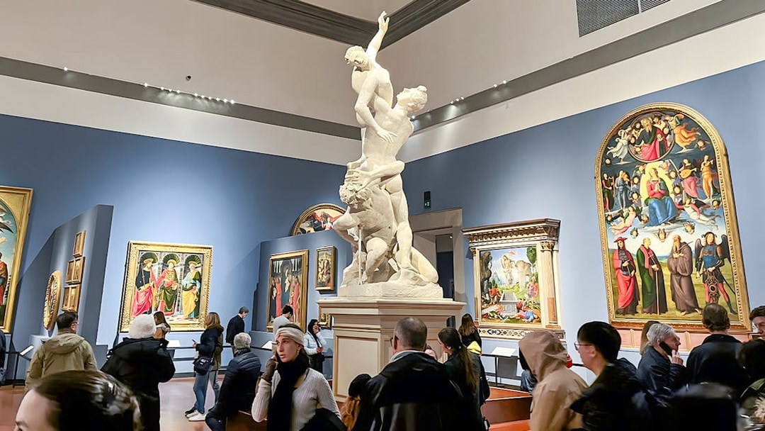 Sculpture of the Rape of Sabine Women at Accademia Gallery, Florence, surrounded by visitors.