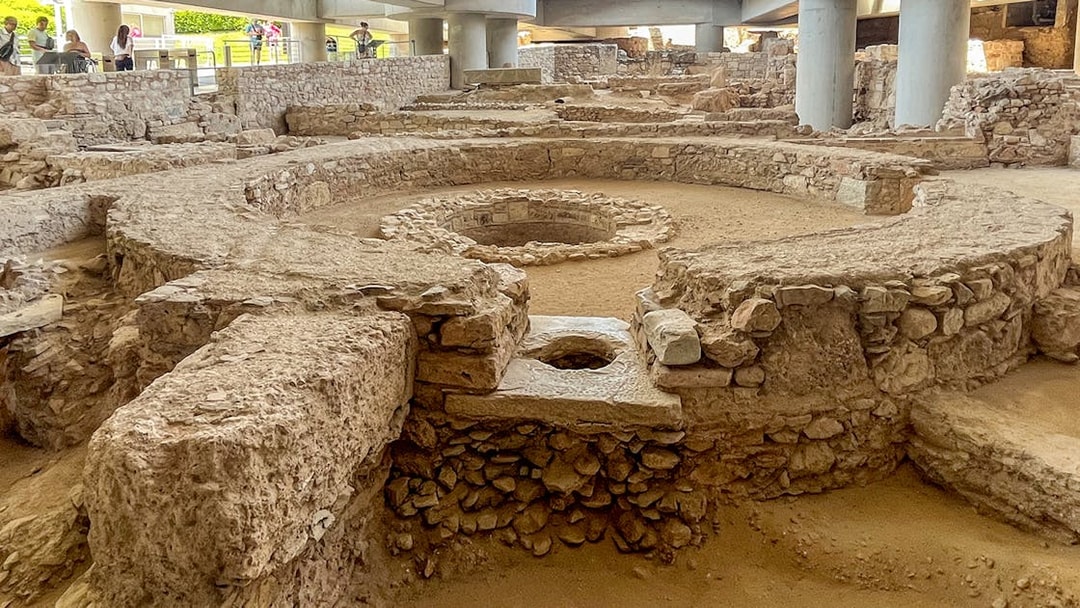 Ancient ruins beneath the Athens Acropolis Museum, showcasing circular stone structures.