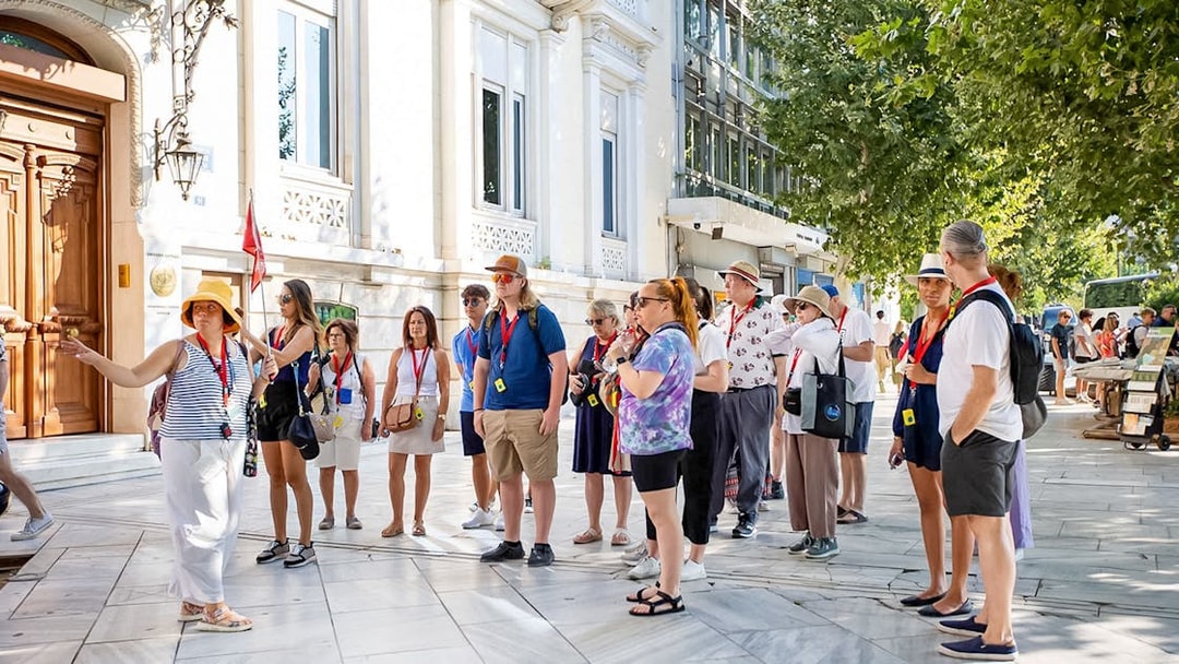 Tour group with audio guides outside Acropolis Parthenon in Athens.