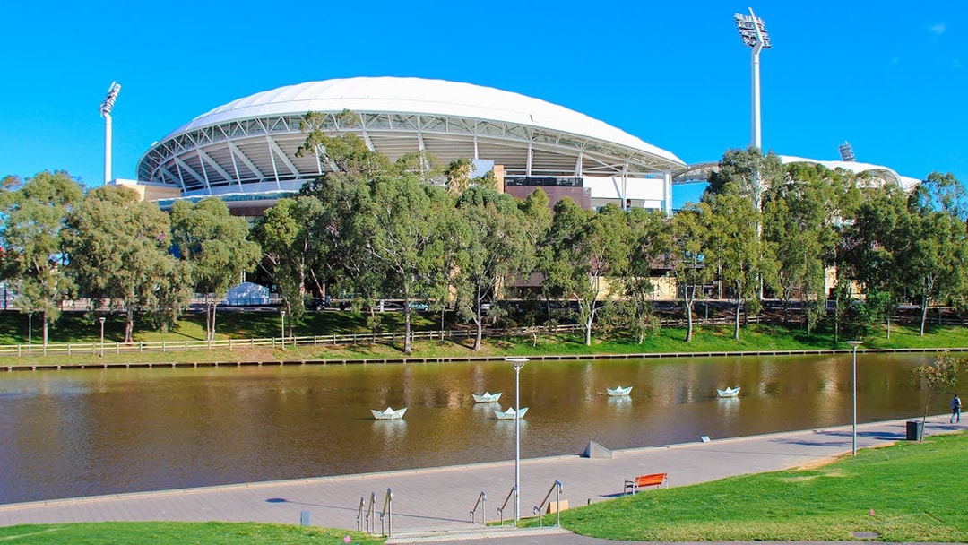 Adelaide Oval Stadium with trees and a lake in the foreground.