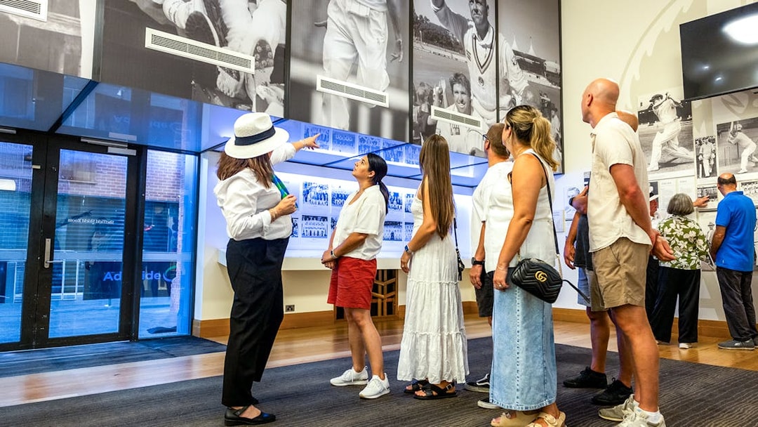 Guide explaining cricket history to visitors at Adelaide Oval Stadium.