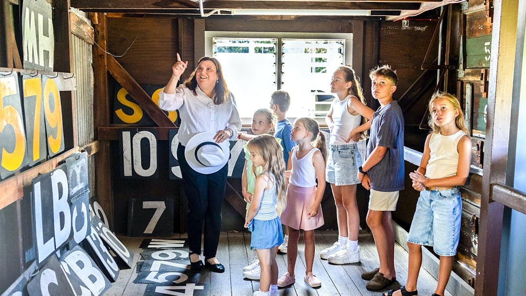 Guide explaining scoreboard numbers to children in a wooden room.