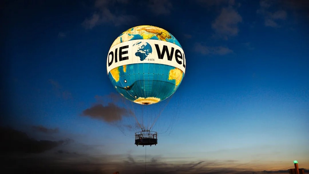 Hot air balloon ascent with "Die Welt" design at dusk, Berlin.