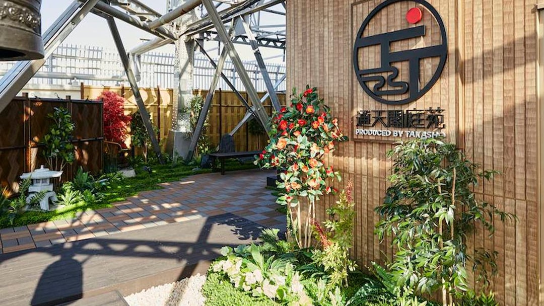 Tsutenkaku Tower garden area with plants and signage in Osaka, Japan.