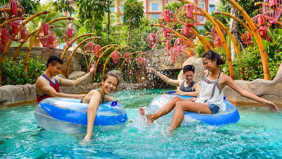 People enjoying the Lazy River at Adventure Cove waterpark, surrounded by tropical plants.