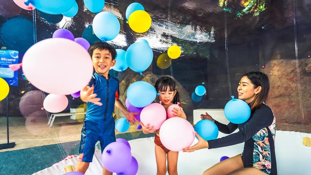 Children playing with colorful balloons at Adventure Cove Waterpark™.