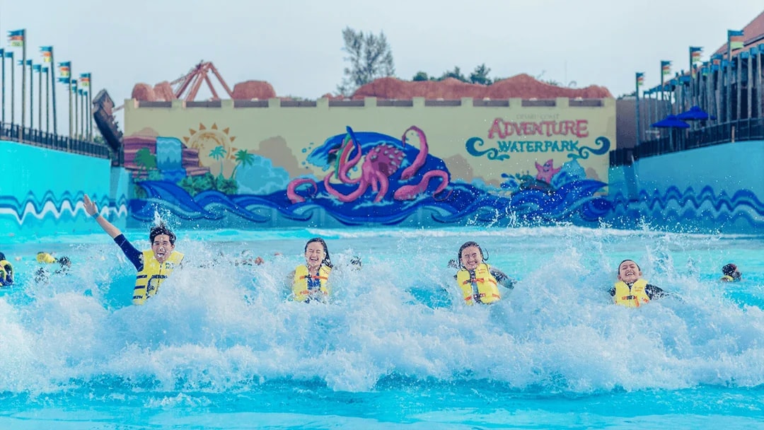 Tourists in life jackets enjoying wave pool at Adventure Waterpark Desaru Coast.
