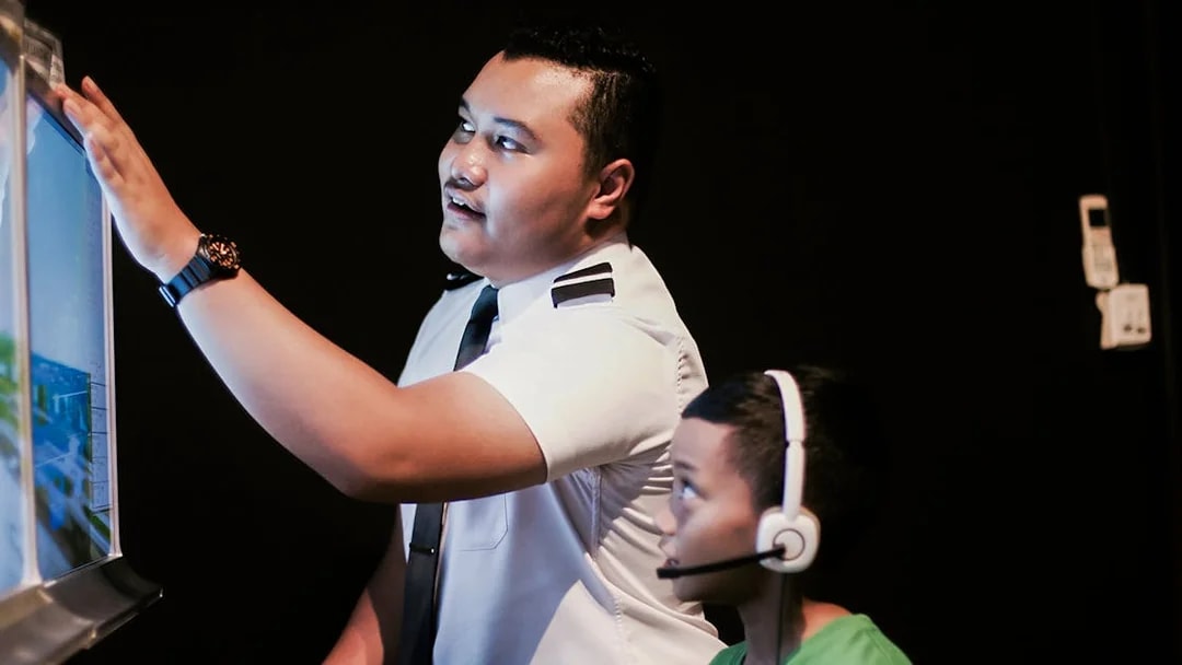 Pilot guiding child in flight simulator during Aeroviation Full Flight Experience.
