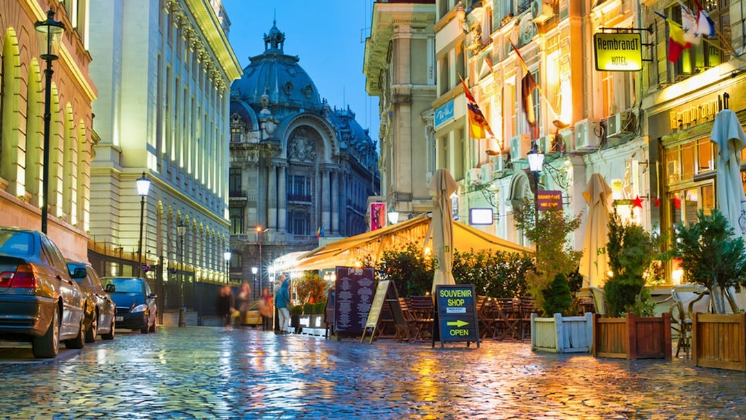 Bucharest street at night with illuminated buildings and outdoor cafes.