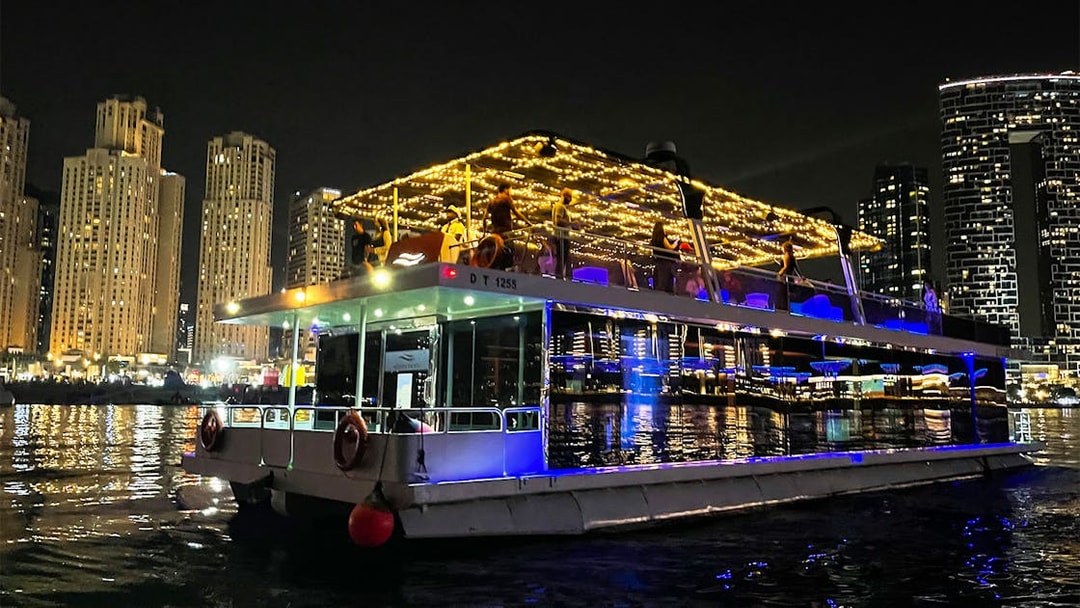 Houseboat with lights on Dubai Marina at night during Ain Dubai tour.