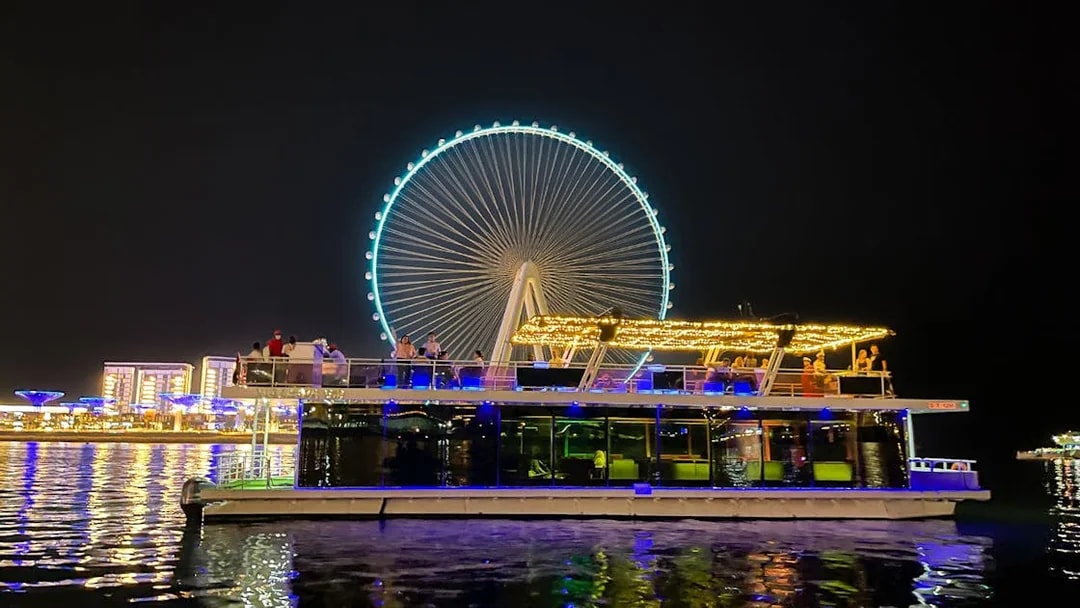 Houseboat on Ain Dubai tour with illuminated Ferris wheel in the background.