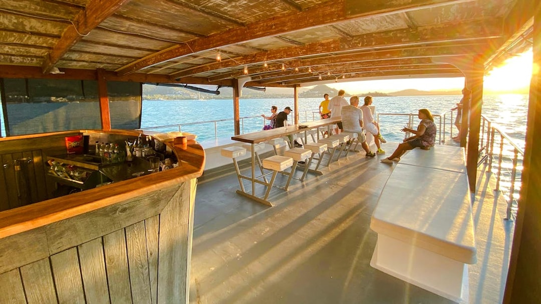 Sundowner cruise bar with people enjoying sunset views at Airlie Beach.