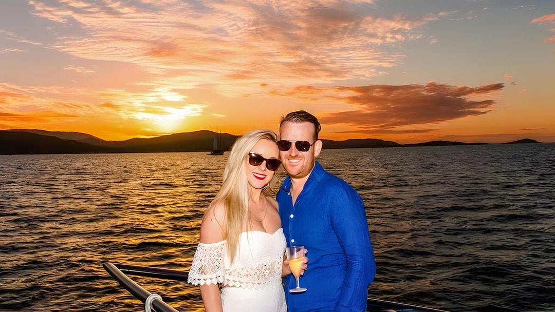 Couple enjoying a sundowner cruise at sunset, Airlie Beach.