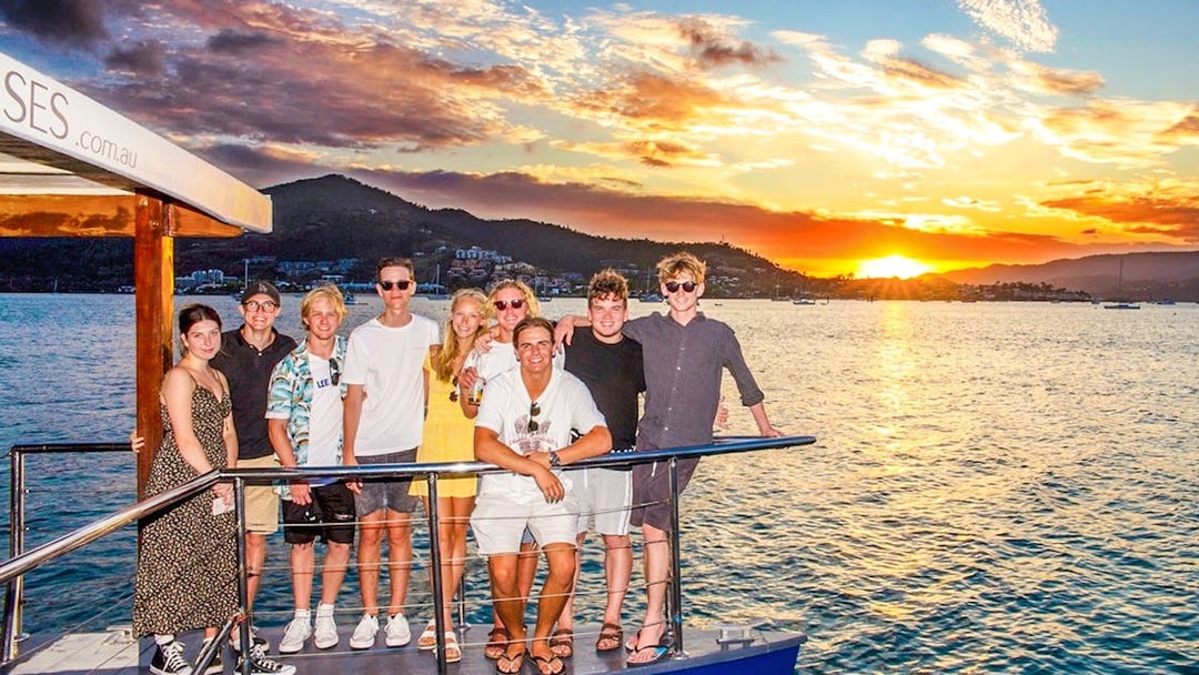 Tourists enjoying a sundowner cruise at sunset near Airlie Beach.