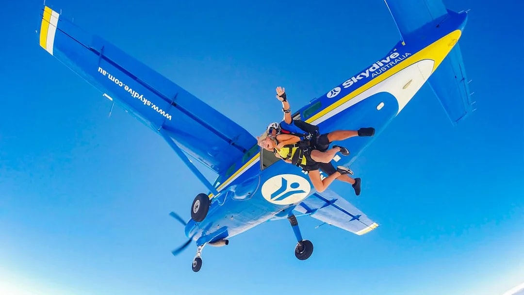 Tandem skydiving over Airlie Beach with instructor and skydiver exiting plane.