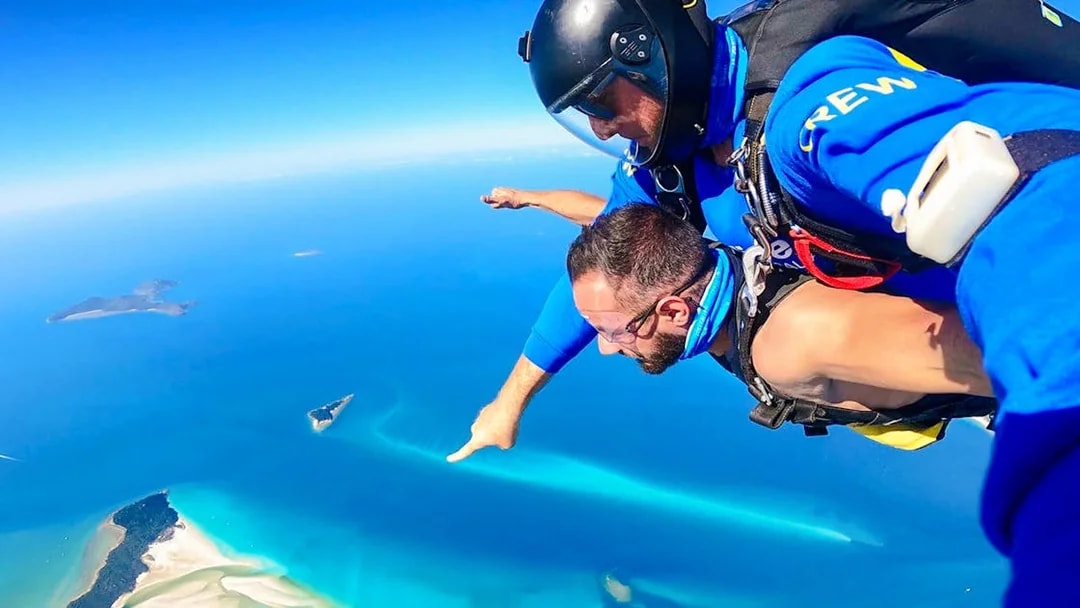 Tandem skydivers over Airlie Beach with Whitsunday Islands in view.