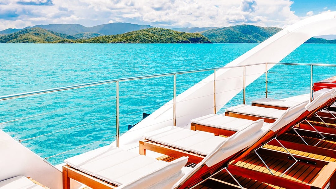 Sun loungers on a boat deck overlooking turquoise waters and islands on the ZigZag Whitsundays Day Tour.