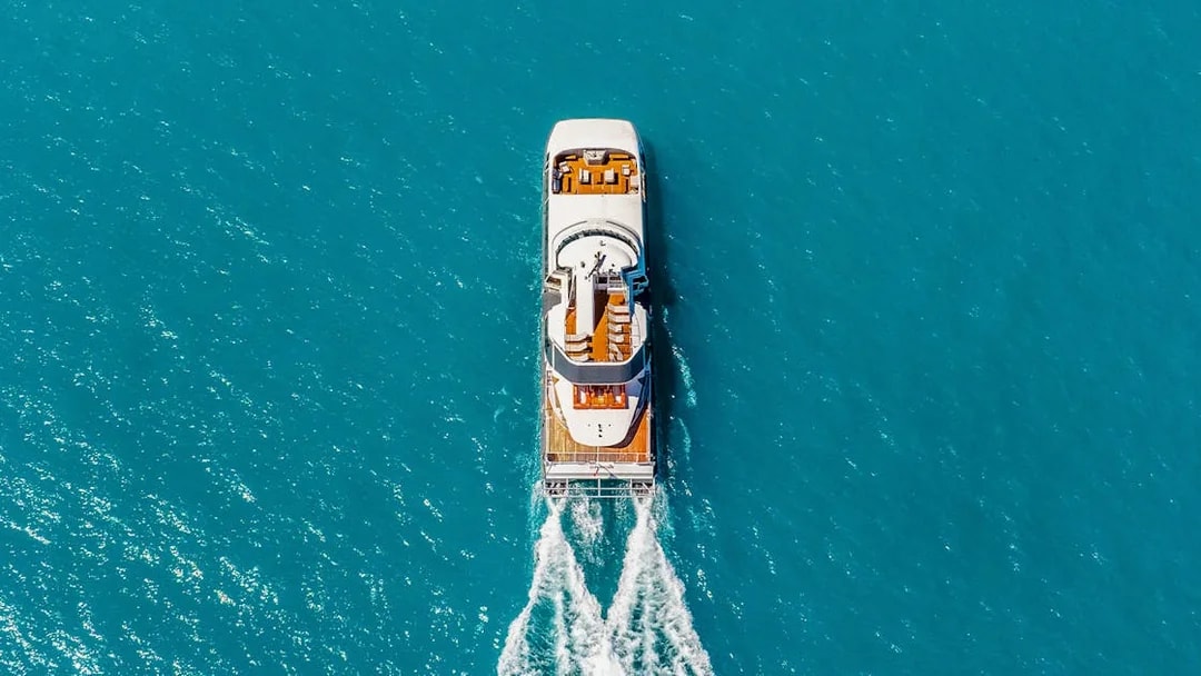 Aerial view of a boat cruising through clear blue waters on the ZigZag Whitsundays Day Tour.