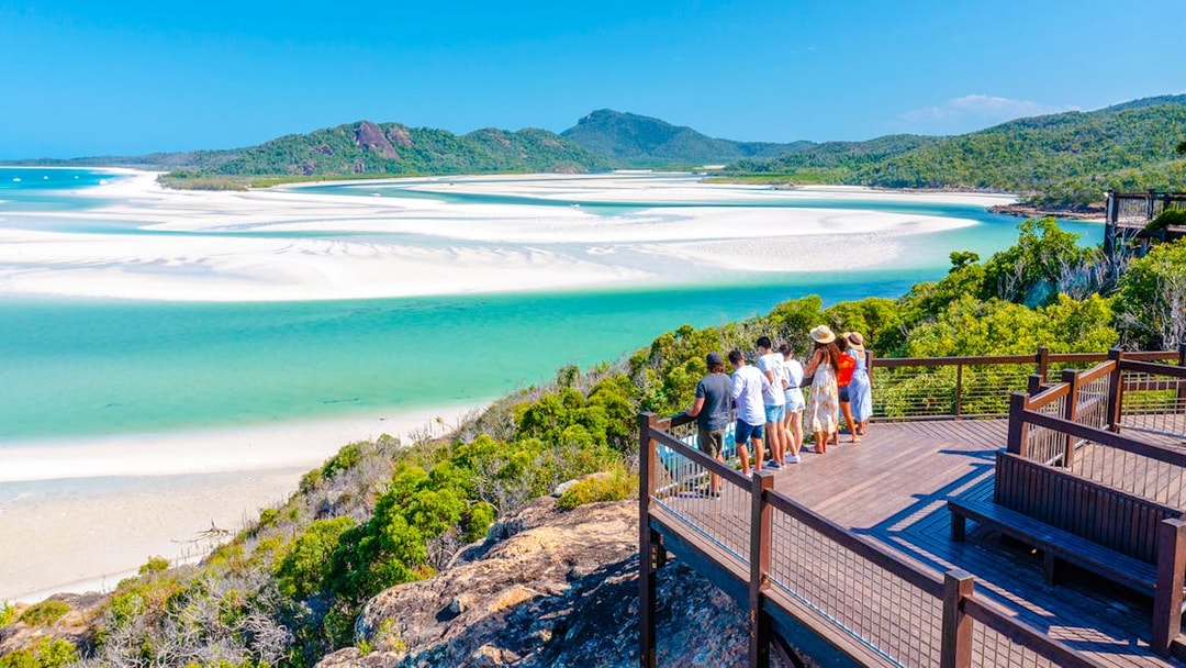 Tourists on a lookout deck viewing Whitehaven Beach's turquoise waters and sandbars, Whitsundays.
