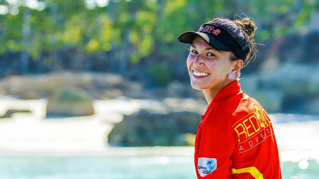 Tour guide smiling on Thundercat Whitsundays Full Day Tour, with beach and trees in background.