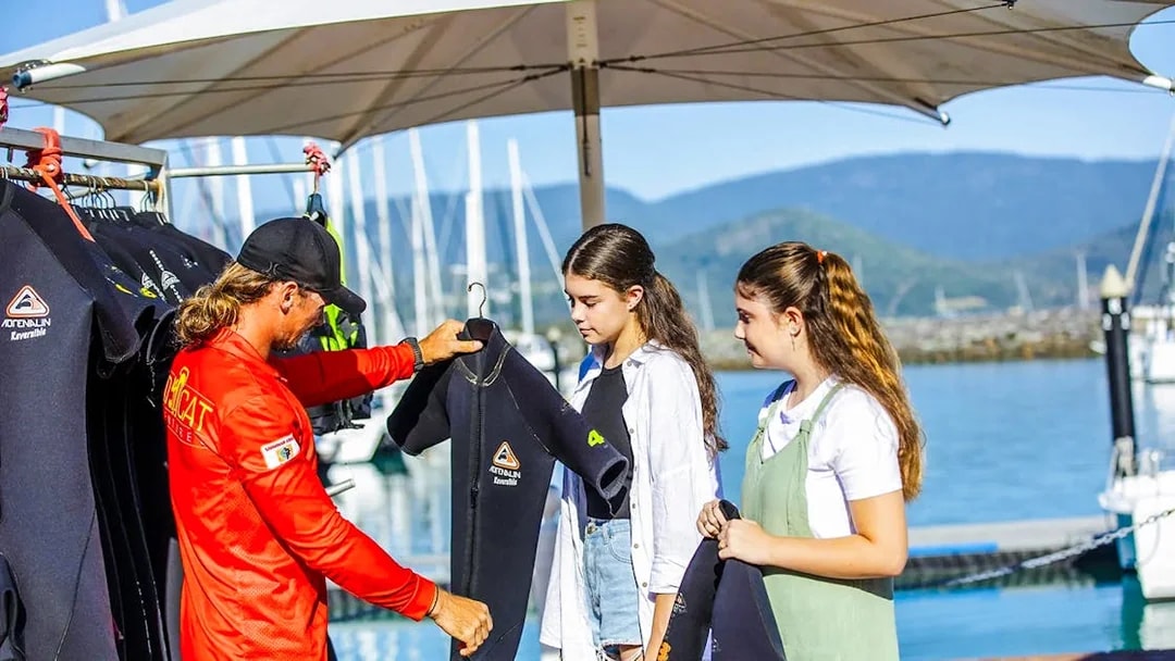 Tour guide handing wetsuits to participants on Thundercat Whitsundays Full Day Tour at marina.