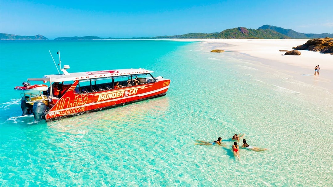 Thundercat boat near Whitsundays beach with people swimming in clear water.