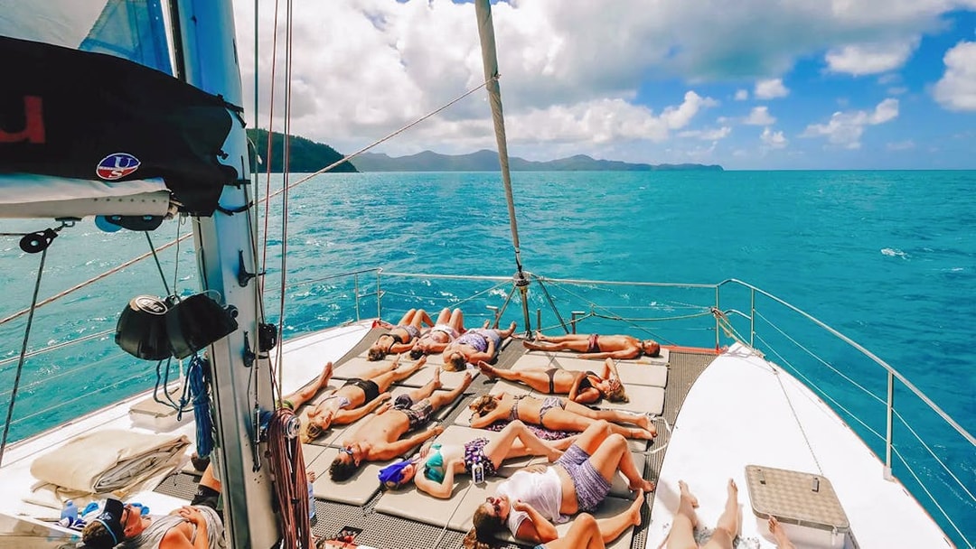 Tourists sunbathing on a sailboat deck in the Whitsundays.