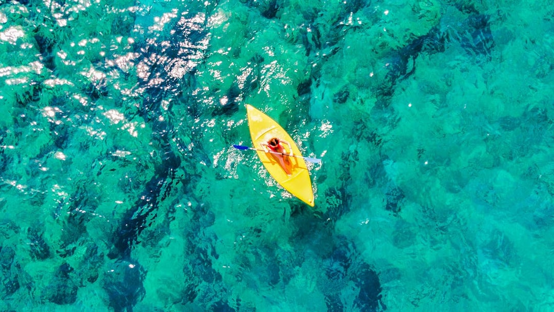 Aerial view of a person kayaking on clear ocean water.