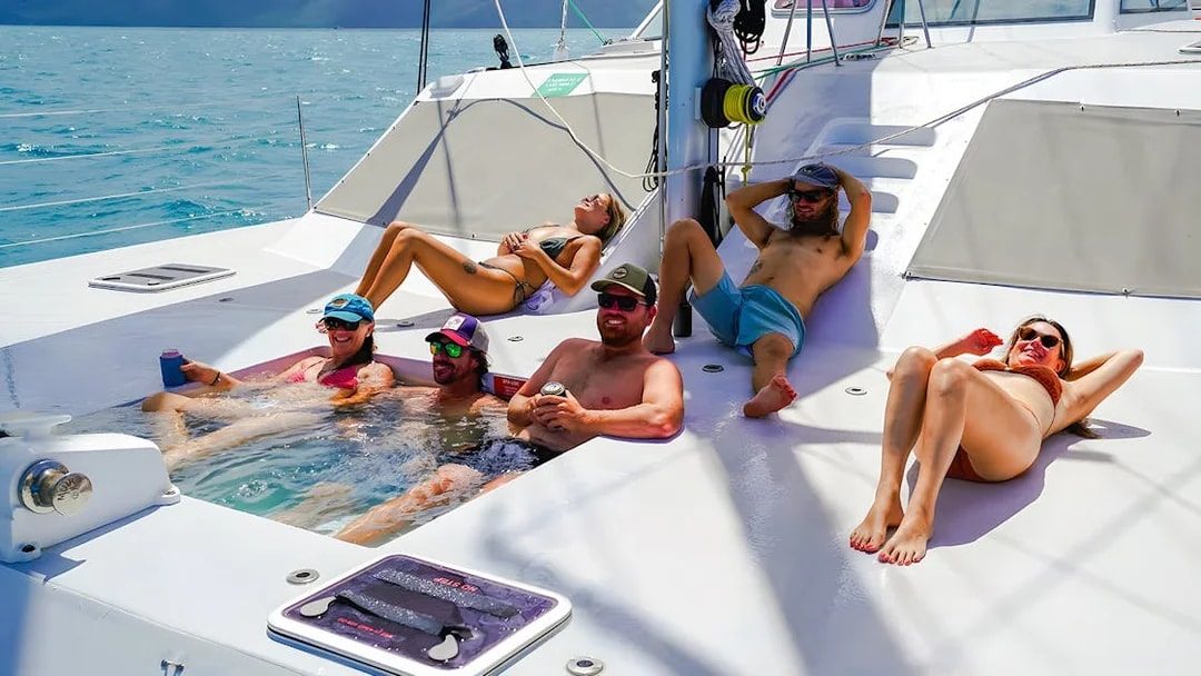 People relaxing in a jacuzzi on the foredeck of a catamaran cruise in the Whitsundays.