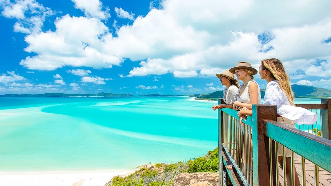 Tourists enjoying the view from Hill Inlet Lookout, Whitsundays, overlooking turquoise waters.