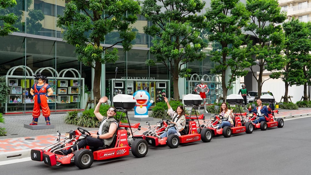 People enjoying Akihabara GoKart Experience in Tokyo, driving past anime statues.