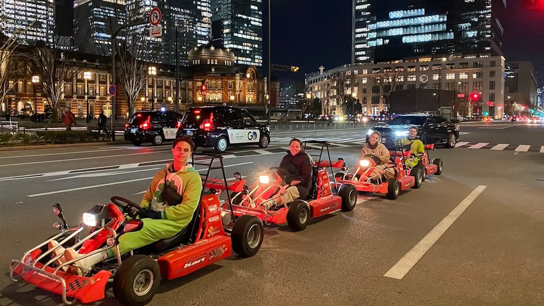 People driving go-karts on Akihabara streets in Tokyo at night.