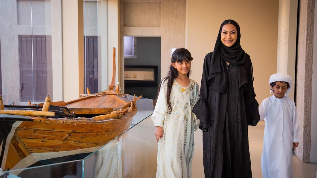 Visitors exploring traditional boat exhibit at Al Shindagha Museum.