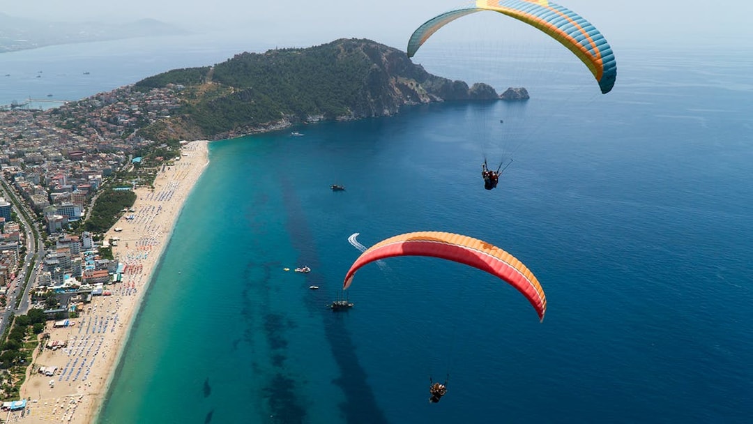 Paragliders soaring over Alanya coastline with city and sea view.