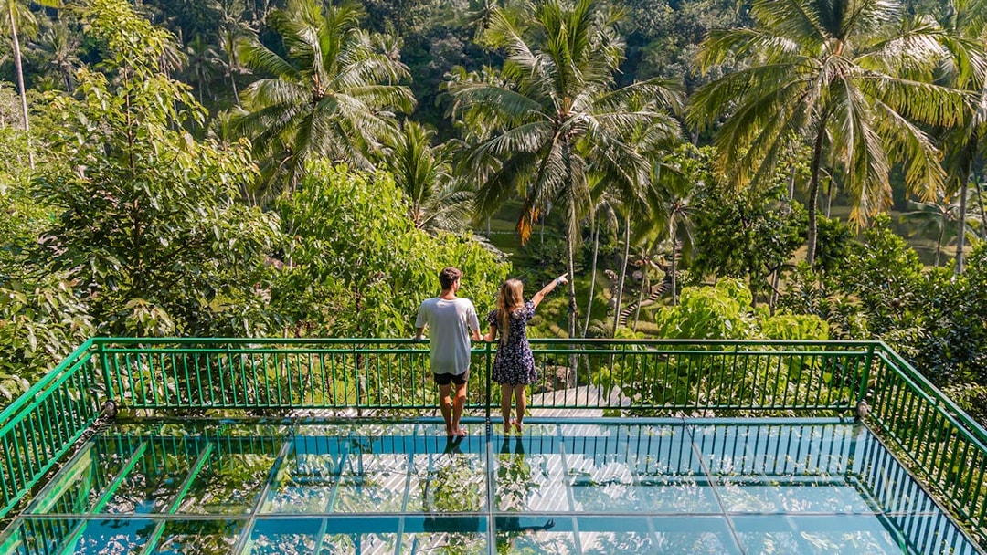 Couple on glass terrace overlooking lush greenery at Alas Harum Bali.