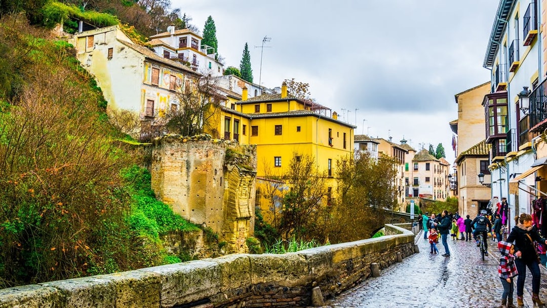 Albaicin street view with colorful houses and tourists walking in Granada, Spain.