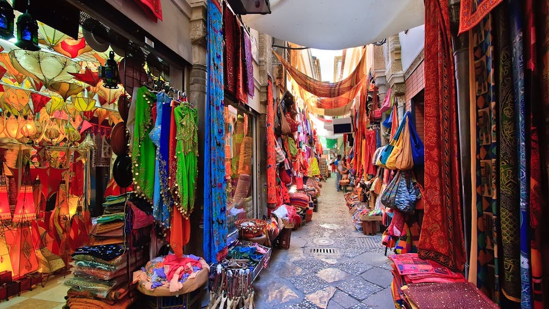 Colorful market street in Albaicin, Granada, with vibrant textiles and lanterns on display.