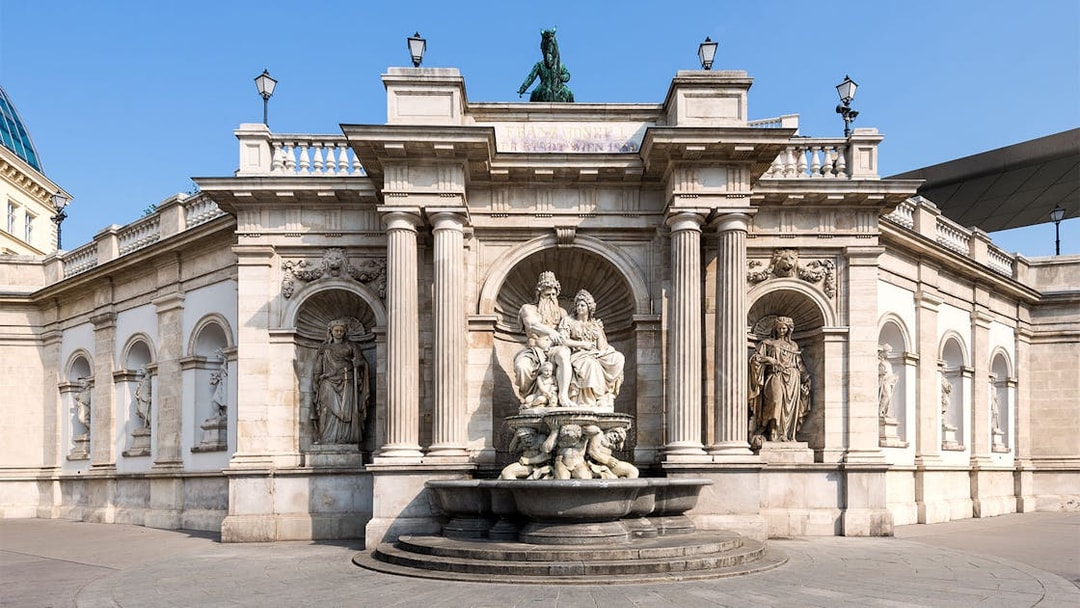 Albertina Museum entrance with ornate statues and fountain in Vienna.
