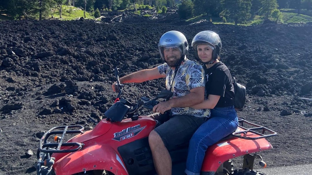 Couple on a quad bike exploring volcanic terrain during Alcantara Gorges tour.