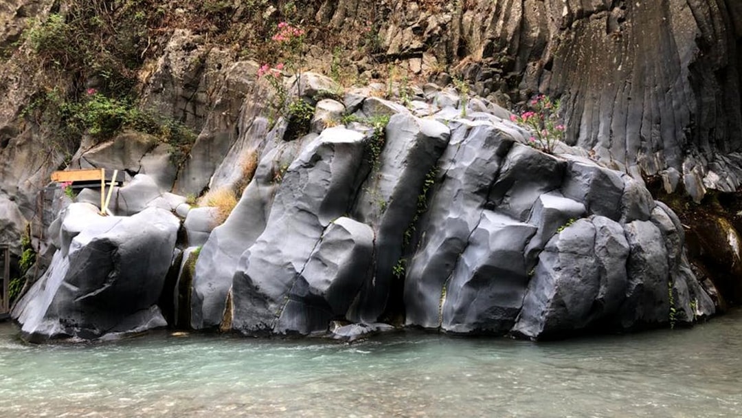 Alcantara Gorges basalt rock formations with clear water stream, Sicily.