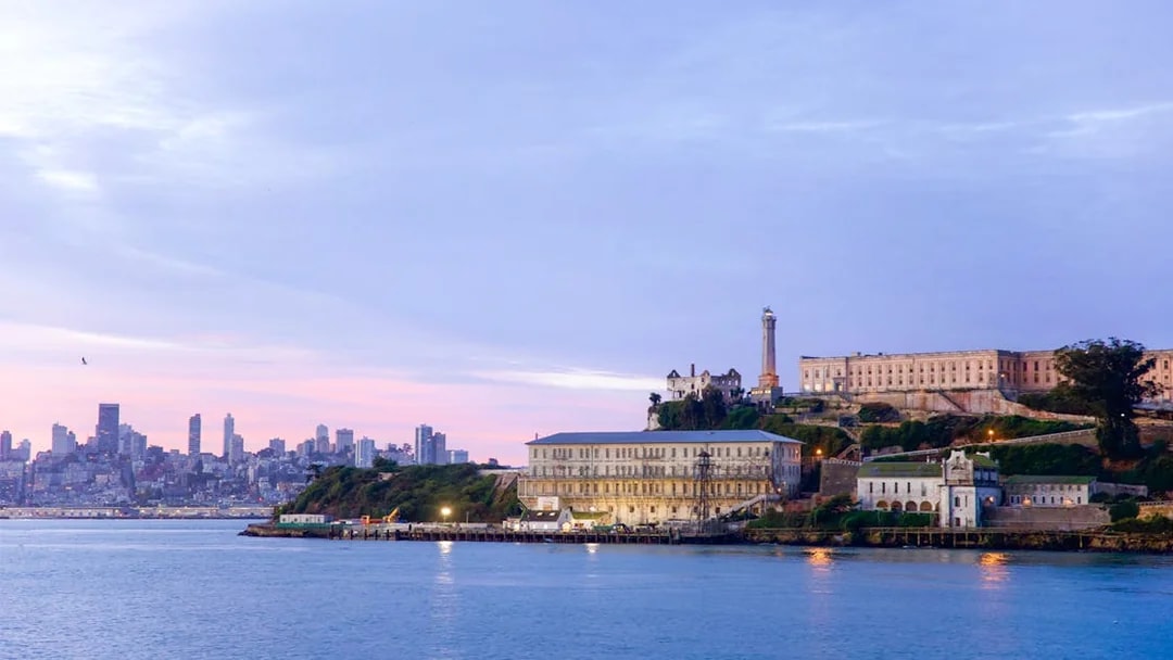 Alcatraz Island with San Francisco skyline at sunset, viewed from the water.