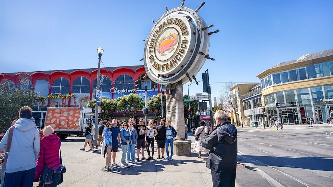Guide photographing tourists at Fisherman's Wharf Crab sign, San Francisco.