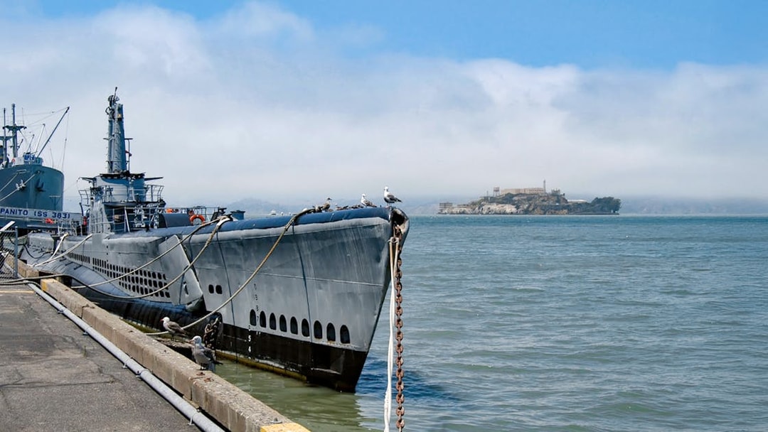 Submarine docked at San Francisco pier with Alcatraz Island in the background.