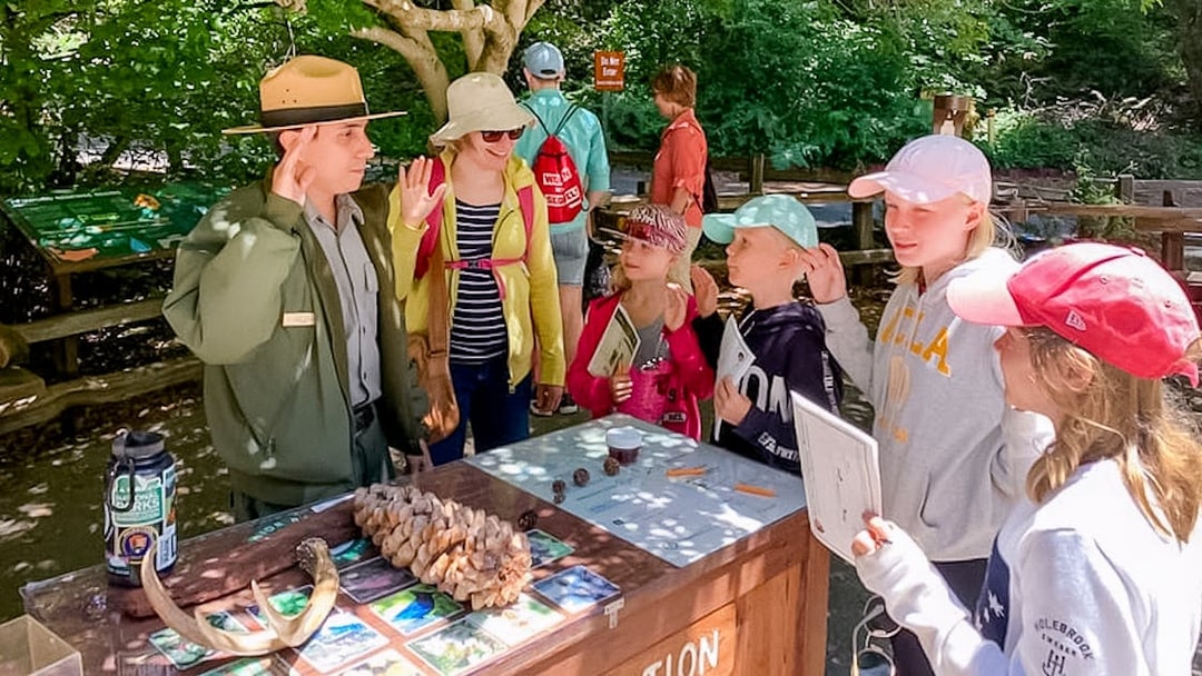 Park ranger engaging with children at an information booth in Muir Woods.