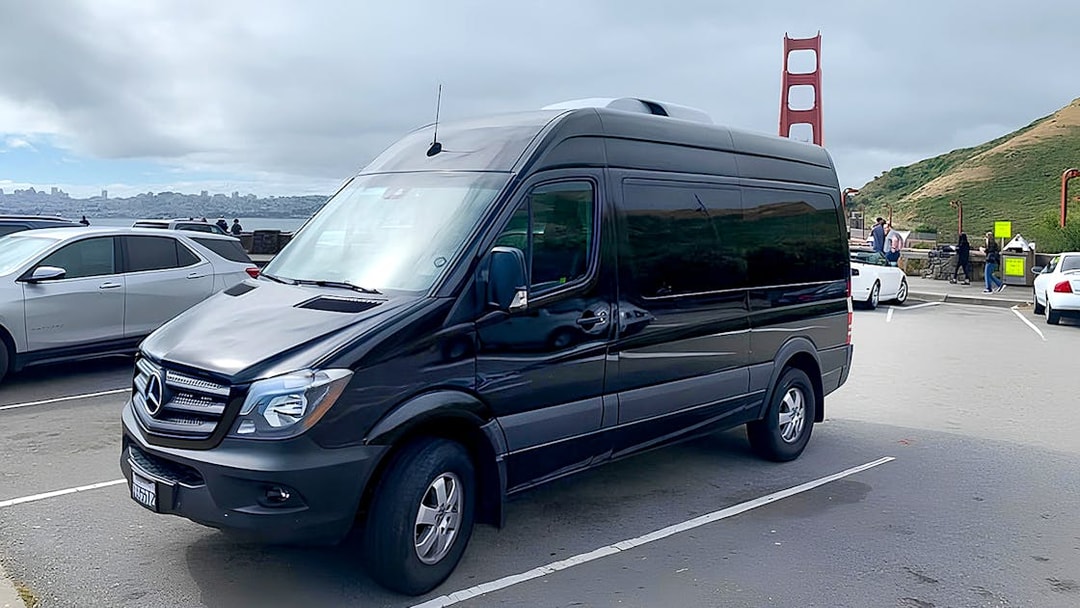 Tour van parked near Golden Gate Bridge for Alcatraz, Muir Woods, and Sausalito tour.