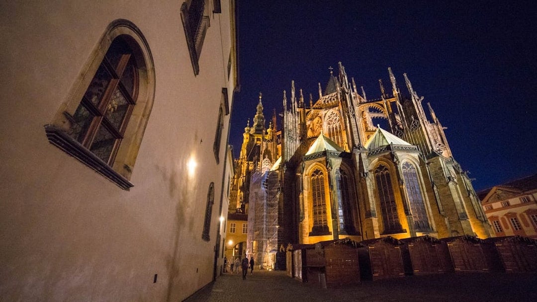 Prague Castle at night with illuminated Gothic architecture.