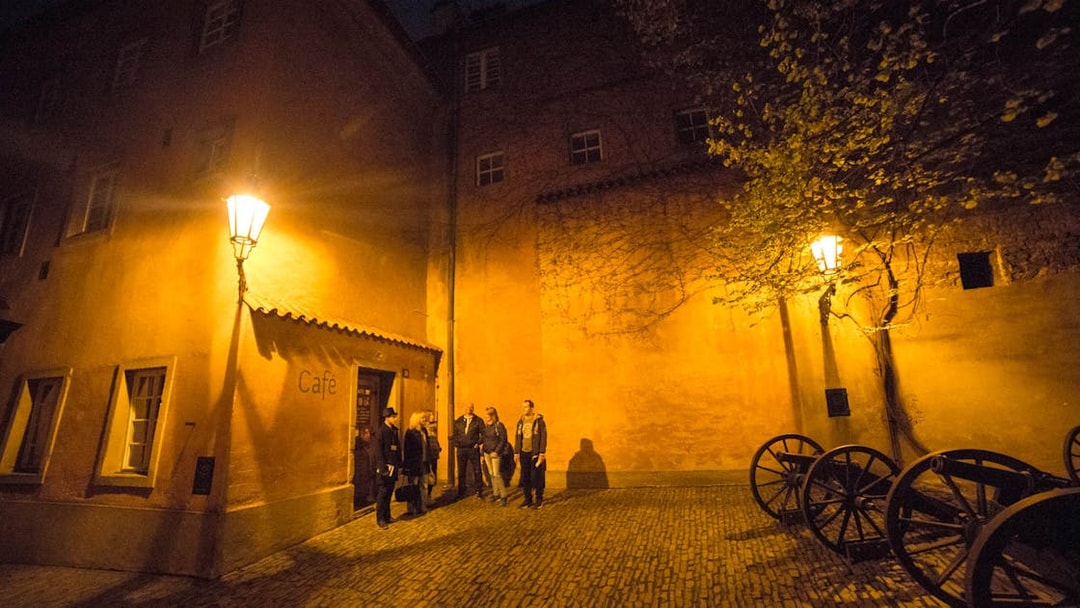 Visitors exploring a dimly lit courtyard near Prague Castle at night.