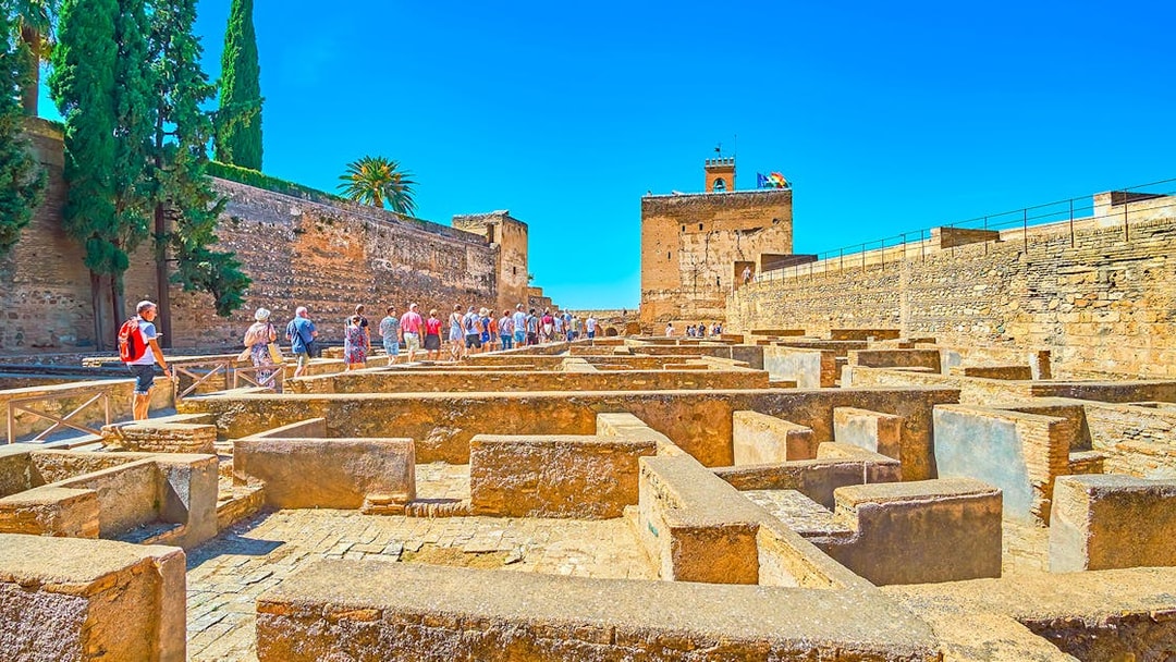 Visitors exploring Alhambra's ancient ruins on a guided tour in Granada, Spain.